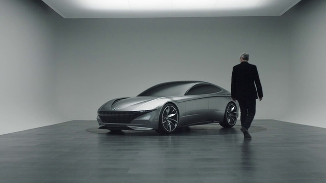 Video Reference: Automotive design, Vehicle, Car, Concept car, Supercar, Sports car, Luxury vehicle, Performance car, Vehicle door, Person, Indoor, Man, Table, Small, Standing, Luggage, Desk, Room, Black, Board, White, Young, Suitcase, Holding, Living, Plane, Wall, Floor, Land vehicle, Automotive, Wheel