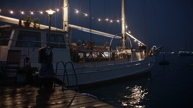 Video Reference: Boat, Vehicle, Watercraft, Ship, Marina, Schooner, Tall ship, Night, Harbor, Sailing ship, Water, Outdoor, Docked, Large, Small, Sitting, Table, Filled, Black, Dock, Body, River, Group, Parked, Floating, Standing, City, Sky, Transport, Sailing vessel