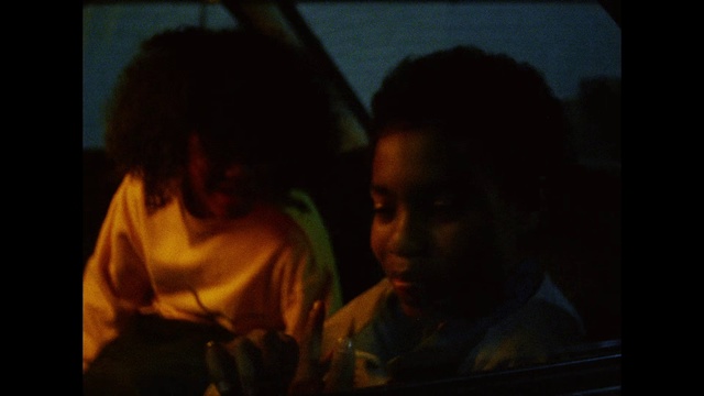 Video Reference: Black, Fun, Darkness, Human, Interaction, Scene, Mouth, Photography, Adaptation, Conversation, Person, Man, Indoor, Front, Looking, Sitting, Screen, Dark, Laptop, Table, Photo, Lit, Woman, Monitor, Television, Holding, Computer, Using, Young, Shirt, Standing, Pizza, Red, Room, Phone, Cat, People, Blurry, Human face, Clothing, Staring