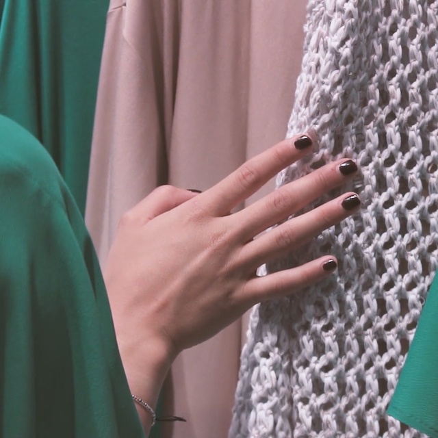 Video Reference: Green, Nail, Finger, Hand, Outerwear, Textile, Dress, Sleeve, Haute couture, Curtain, Clothing, Person, Indoor, Sitting, Man, Shirt, Laptop, Woman, Wearing, Looking, Using, Table, Hair, Computer, Young, White, Holding, Fashion accessory