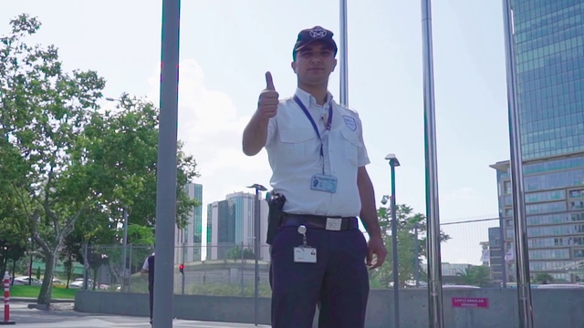 Video Reference: Standing, Urban area, Uniform, Tree, Architecture, Photography, City, Plant, Gesture, Official
