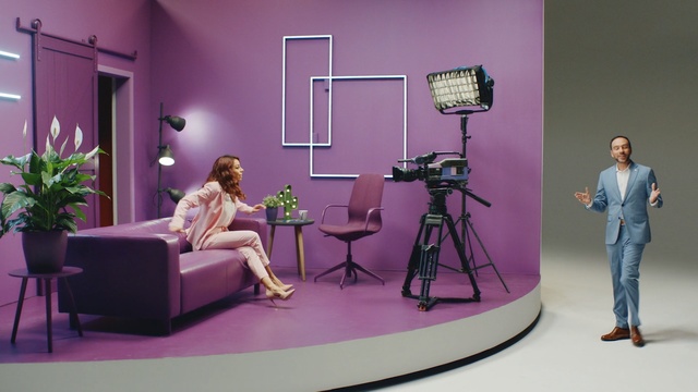 Video Reference: Purple, Television studio, Furniture, Film studio, Design, Interior design, Room, Table, Indoor, Pink, Living, Sitting, Standing, Woman, Bedroom, Glass, Holding, Large, Black, Screen, Bed, Television, Desk, Mirror, Man, Playing, White, Phone, Video, Bear, Wall, Chair, Floor, Person, Clothing