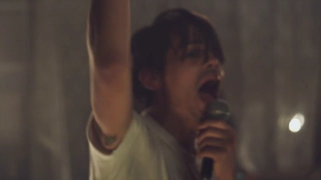 Video Reference: singer, microphone, performance, concert, vocalist, raised arm, indoor, dim light, close-up, music, blurred, live show