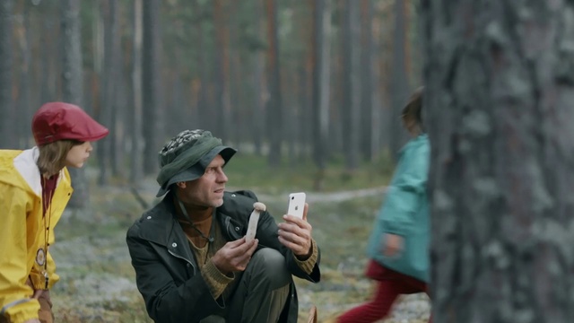 Video Reference: Woodland, Forest, Adaptation, Recreation, Photography, Person, Outdoor, Building, Uniform, Man, Holding, Cellphone, Park, Phone, Woman, Wearing, Young, Street, Bench, Sitting, Talking, People, Walking, Standing, Boy, Playing, Hat, Ball, Group, City, Riding, Field, Clothing, Jacket, Human face, Military uniform