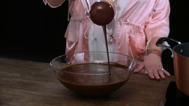 Video Reference: Chocolate, Food, Table, Person, Indoor, Wine, Sitting, Cup, Wooden, Front, Glasses, Man, Glass, Holding, Bowl, Woman, Kitchen, Standing, Red, Plate, Tableware