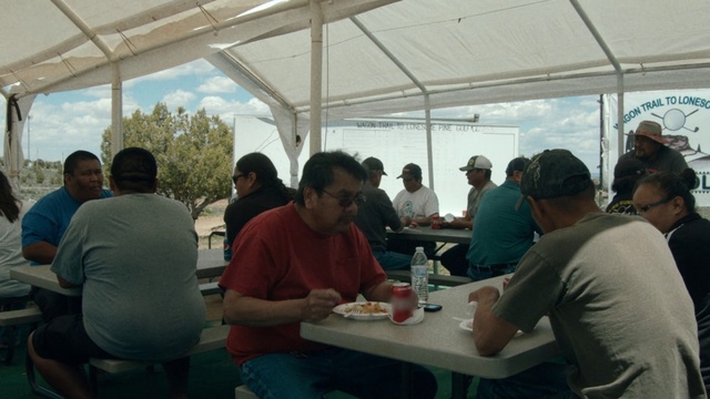 Video Reference: Event, Community, Lunch, Meal, Recreation, Table, Picnic, Brunch, Taste, Person, Indoor, People, Group, Sitting, Man, Food, Building, Eating, Standing, Wine, Woman, Room, Clothing, Bottle