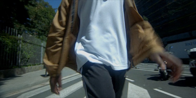 Video Reference: Photograph, Clothing, Jeans, Snapshot, Jacket, Street fashion, Denim, Fashion, Outerwear, Footwear, Person, Road, Outdoor, Man, Wearing, Young, Street, Riding, Woman, Holding, Shirt, Blue, Standing, People, Trousers, Luggage and bags, Handbag