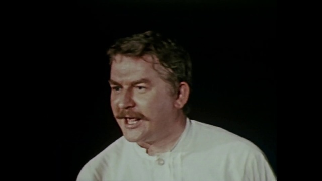 Video Reference: Face, Forehead, Chin, Cheek, Nose, Photograph, Facial expression, Head, Portrait, Skin, Person, Man, Indoor, Looking, Front, Holding, Shirt, Standing, Dark, Laptop, Wearing, Sitting, Young, White, Glasses, Computer, Table, Game, Room, Cake, Video, People, Remote, Red, Wedding, Playing, Human face, Clothing, Male