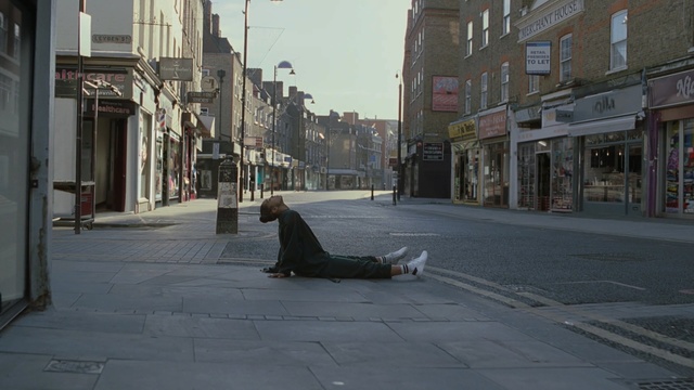 Video Reference: Street, Town, Snapshot, Road, Urban area, Sitting, Infrastructure, Neighbourhood, Road surface, City