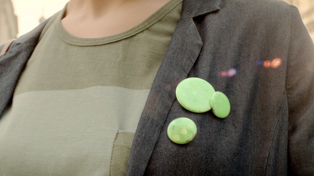 Video Reference: green, button, outerwear, neck, Person