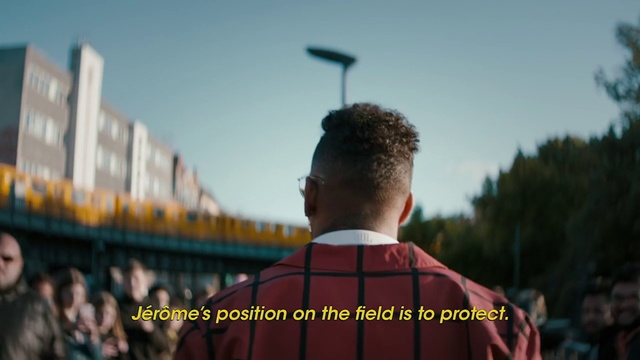 Video Reference: Sky, Photography, Outerwear, Temple, Crowd, Uniform, Academic dress, Person, Outdoor, Man, Standing, Front, Red, Holding, Looking, Wearing, Shirt, Hand, Young, Water, Large, Phone, Riding, Flying, Street, Sign, Player, Field, Blue, City, Clothing