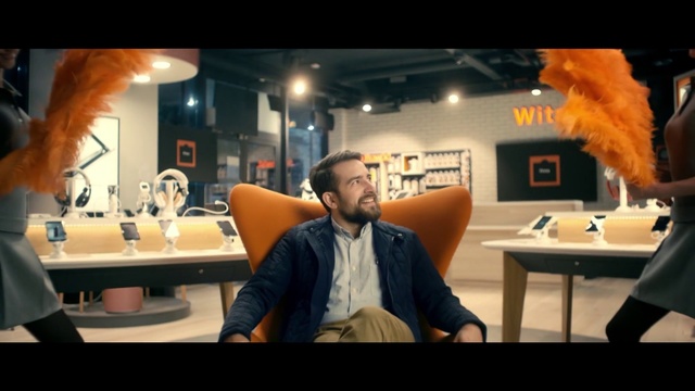 Video Reference: Man, Woman, Chair, Score, Beard, Person, Indoor, Table, Front, Looking, Standing, Food, Wearing, Television, Kitchen, Mirror, People, Computer, Sink, Group, White, Room, Furniture, Clothing, Human face, Laptop, Text