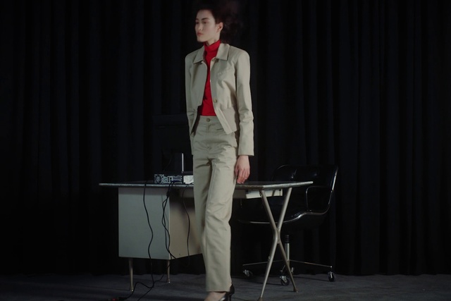 Video Reference: Performance, Suit, Gentleman, Standing, Talent show, Performing arts, Event, Formal wear, Scene, Public speaking, Person, Curtain, Necktie, Man, Front, Holding, Wearing, Dressed, Black, Dress, Suitcase, Dark, White, Table, Woman, Red, Room, Young, Phone, Luggage, Clothing, Floor, Furniture, Piano, Microphone