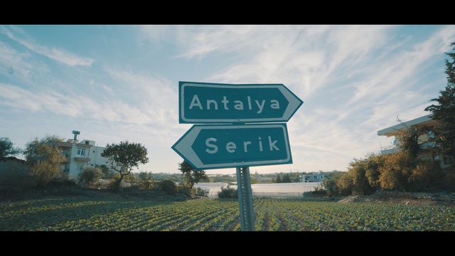 Video Reference: Street sign, Sky, Road, Signage, Natural landscape, Text, Sign, Traffic sign, Cloud, Infrastructure