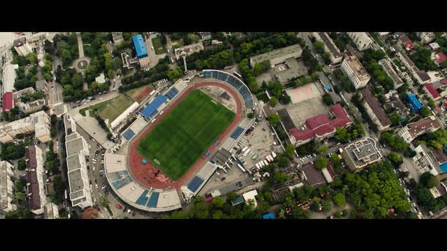 Video Reference: Aerial photography, Sport venue, Stadium, Bird-eye view, Urban area, Metropolitan area, Urban design, Residential area, Human settlement, Soccer-specific stadium, Person, Food, City, Aerial