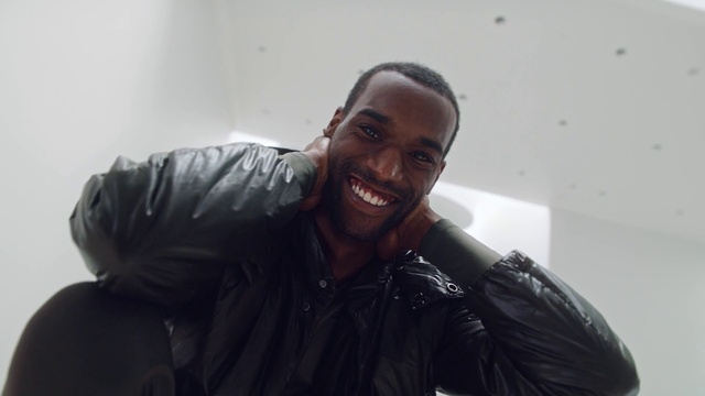 Video Reference: Smile, Outerwear, Flash photography, Jaw, Sleeve, Beard, Gesture, Happy, Facial hair, Audio equipment