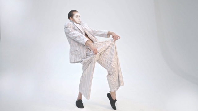Video Reference: White, Clothing, Outerwear, Suit, Footwear, Neck, Trousers, Formal wear, Robe, Beige
