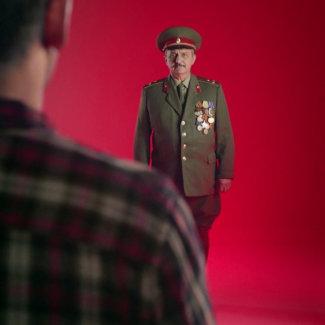 Video Reference: Gentleman, Tartan, Male, Design, Pattern, Fashion, Plaid, Outerwear, Textile, Formal wear, Person, Man, Standing, Indoor, Clothing, Wearing, Uniform, Holding, Looking, Front, Red, Suit, Hand, Woman, Young, Glasses, Room, Hat, Shirt, Phone, People, Fashion accessory, Human face, Coat, Fedora, Tie, Official, Blazer