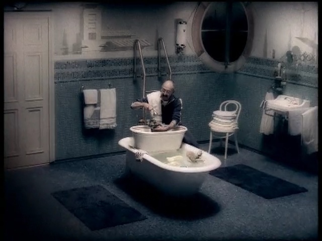 Video Reference: room, bathroom, toilet, interior design, floor, plumbing fixture, flooring, darkness, design, sink, Person