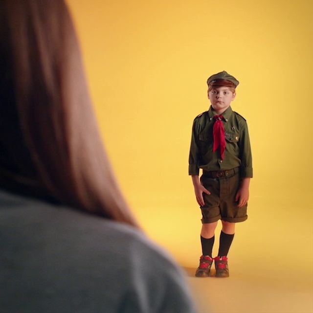 Video Reference: Fashion, Human, Gentleman, Fashion design, Fun, Headgear, Photography, Performance, Person, Indoor, Man, Standing, Wearing, Looking, Holding, Yellow, Young, Woman, Room, Playing, Game, Clothing, Jacket, Coat, Human face, Footwear, Smile, Outerwear, Fashion accessory