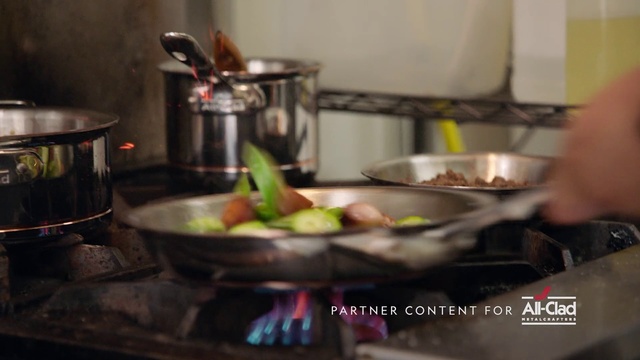 Video Reference: Food, Meal, Dish, Cookware and bakeware, Cooking, Cuisine, Wok, Recipe, Brunch, À la carte food, Indoor, Kitchen, Counter, Preparing, Making, Woman, Standing, Man, Sitting, Pot, Large, Stove, Table, Steel, Stainless, Pan, Sink, Bowl, Plate, White, Sandwich, Wall, Vegetable, Fast food, Fruit, Mixing bowl, Home appliance, Cluttered, Kitchen appliance