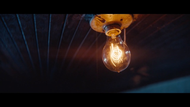 Video Reference: Light, Lighting, Yellow, Light fixture, Incandescent light bulb, Sky, Atmosphere, Ceiling, Space, Photography, Sitting, Table, Glass, Dark, Small, Holding, Man, Red, Lamp, Light bulb, Amber, Lantern