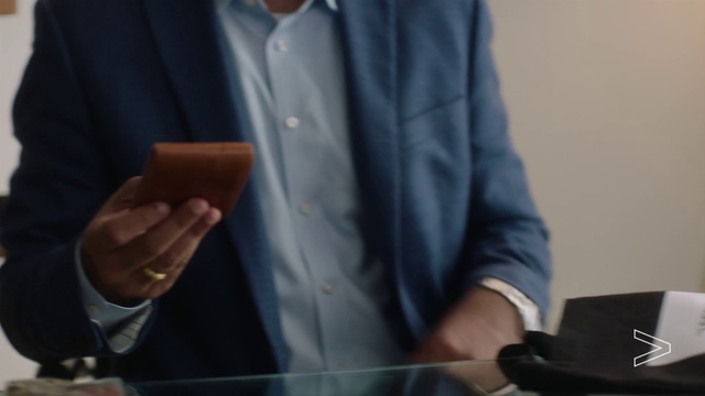 Video Reference: Suit, Formal wear, Gentleman, Tie, Tuxedo, Outerwear, Blazer, White-collar worker, Hand, Finger, Person, Man, Indoor, Holding, Standing, Table, Front, Using, Food, Wearing, Black, Glasses, Woman, Shirt, Young, Cake, Cutting, Kitchen, Blue, People, Room, Clothing, Watch, Microphone