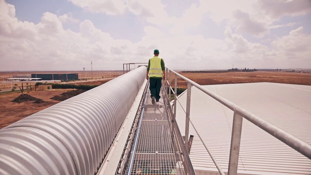 Video Reference: Bridge, Walkway, Architecture, Nonbuilding structure, Boardwalk, Photography, Cable-stayed bridge, Leisure, Guard rail, Pedestrian, Person, Outdoor, Fence, Building, Sitting, Water, Standing, Plane, Walking, Board, Large, Track, Dock, Man, Cloudy, Train, Airplane, People, Boat, White, Blue, Parked, Sky, Clothing, Day