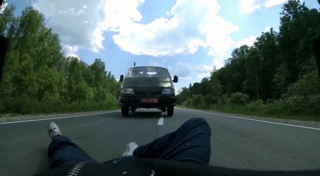 Video Reference: Land vehicle, Vehicle, Motor vehicle, Mode of transport, Car, Road, Asphalt, Lane, Road trip, Automotive exterior, Outdoor, Person, Man, Grass, Street, Riding, Motorcycle, Driving, Woman, Highway, Green, Traveling, Plane, Traffic, Board, Standing, People, Tree, Sky, Auto part, Wheel, Scene, Way, Vehicle registration plate, Text, Van, Cloud, Tire