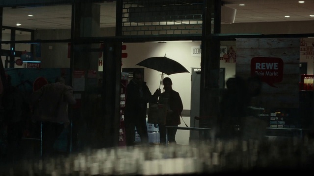 Video Reference: Umbrella, Building, Human, Standing, Architecture, Grey, Automotive design, Shade, Automotive lighting, Tints and shades