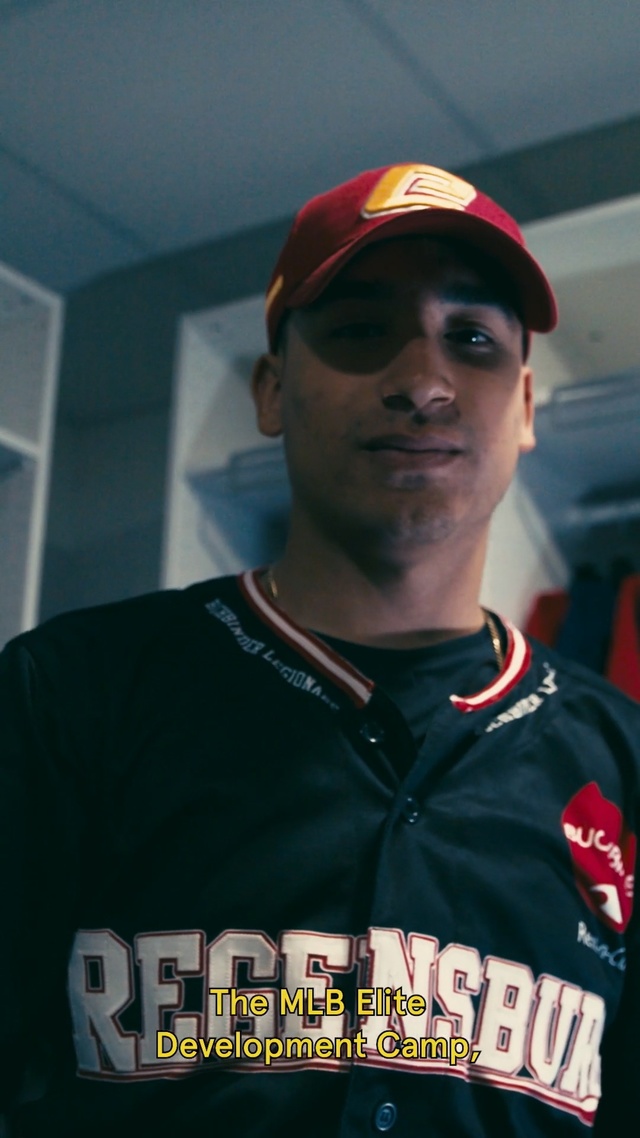 Video Reference: Sports uniform, Forehead, T-shirt, Cool, Eyewear, Uniform, Cap, Person, Baseball, Player, Holding, Man, Wearing, Bat, Shirt, Standing, Hand, Hat, Game, Black, Field, Red, Young, Ball, Batter, Glove, Pitch, Playing, Human face, Clothing, Text, Fashion accessory