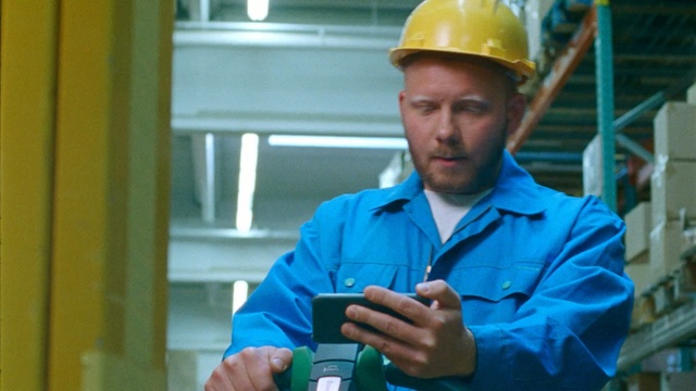 Video Reference: Blue-collar worker, Engineer, Personal protective equipment, Hard hat, Job, Headgear, Workwear, Engineering, Fashion accessory, Electrical contractor, Person, Building, Cellphone, Phone, Outdoor, Holding, Man, Wearing, Using, Blue, Looking, Young, Hat, Woman, Boy, Shirt, Talking, Standing, Clothing, Human face, Helmet, Firefighter