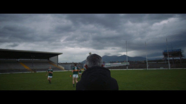 Video Reference: Sport venue, Atmosphere, Sky, Stadium, Cloud, Player, Soccer-specific stadium, Grass, Sports equipment, Photography, Outdoor, Cloudy, Field, Sitting, Man, Standing, Photo, Clouds, Looking, Front, Green, Watching, Large, Dark, Game, Airplane, Red, Flying, Kite, Plane, Ball, Air, People, Playing, Woman, Sign, White, Grassy, Group, Blue, Soccer, Person, Day