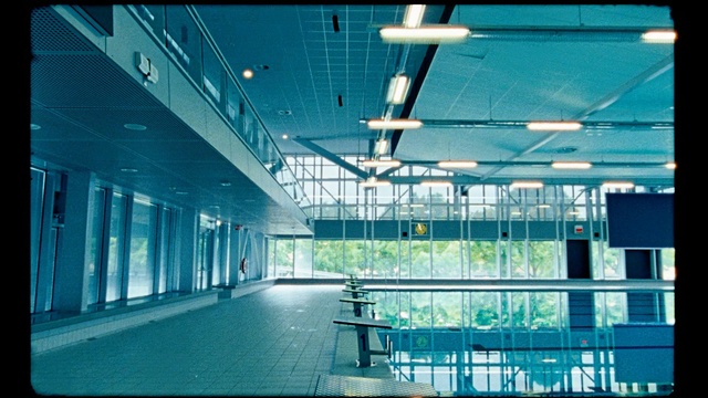 Video Reference: Blue, Turquoise, Architecture, Building, Ceiling, Sky, Glass, Daylighting, Room, Interior design, Window, Man, Riding, Empty, Jumping, Trick, Large, Bench, Air, Green, Ramp, Platform, Doing, Airplane, Luggage, Water, Bridge, Board, Standing, White, City, Furniture, Table, Chair