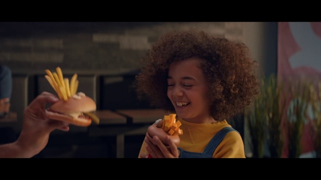 Video Reference: Hairstyle, Yellow, Eating, Junk food, Fun, Human, Smile, Fast food, Photography, American food, Person, Fire, Food, Woman, Table, Young, Holding, Man, Sitting, Standing, Sandwich, Restaurant, Cake, Pizza, Plate, White, People, Snack