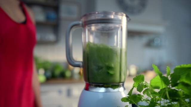 Video Reference: Drink, Vegetable juice, Smoothie, Blender, Health shake, Juice, Food, Small appliance, Home appliance, Aojiru, Indoor, Person, Table, Kitchen, Red, Sitting, Counter, Small, Standing, Little, Woman, Computer, Holding, Laptop, Young, Cake, Pizza, Plate, White, Blue, Sandwich, Man, Glass, Soft drink, Tea, Kitchen appliance, Coffee, Mason jar, Food processor