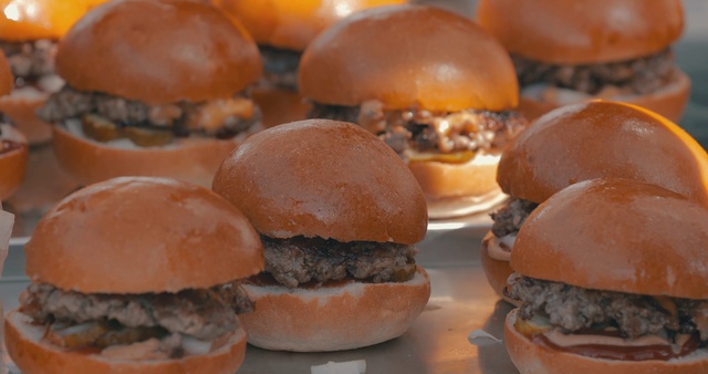 Video Reference: Dish, Food, Hamburger, Cuisine, Cheeseburger, Buffalo burger, Slider, Breakfast roll, Fast food, Ingredient, Person, Table, Sitting, Sandwich, Doughnut, Plate, Donut, Filled, Large, Orange, Close, White, Bun, Covered, Fruit, Cake, Holding, Meat, Oranges, Cheese, Fries, Baked goods, Dessert, Chocolate, Bread, Snack, Veggie burger, Patty, Delicious, Breakfast sandwich, Cemita, Snack food