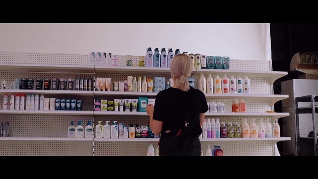 Video Reference: Product, Shelf, Beauty, Snapshot, Shelving, Blond, Bookcase, Room, Furniture, Photography, Person, Indoor, Man, Front, Holding, Open, Food, Counter, Woman, Standing, Table, Refrigerator, Large, Young, Kitchen, White, Bookshelf, Text, Clothing, Convenience store, Bottle