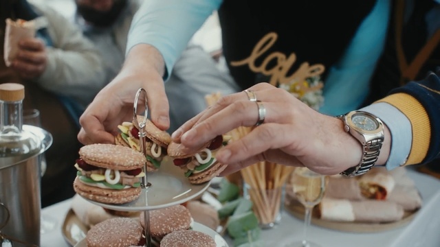 Video Reference: Food, Cuisine, Dish, Finger food, Hand, Dessert, Baked goods, Taste, Eating, Buttercream, Person, Table, Indoor, Plate, Woman, Coffee, Cup, Sitting, Preparing, Sandwich, Cutting, Kitchen, Cake, People, Man, Restaurant, Holding, Fast food, Meal