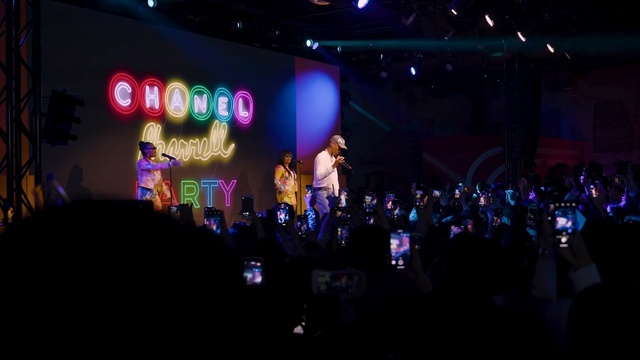 Video Reference: Performance, Entertainment, Stage, Performing arts, Event, Concert, Public event, Rock concert, Music venue, Crowd, Person, Indoor, Monitor, Front, Group, Standing, Sitting, People, Watching, Screen, Room, Man, Large, Computer, Television, Many, Table, Night, Store, Holding, Display, Video, Light, Music, Musical instrument, Guitar, Drum
