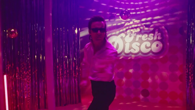 Video Reference: Pink, Violet, Magenta, Purple, Light, Visual effect lighting, Person, Man, Holding, Front, Standing, Stage, Woman, Wearing, Smiling, Dark, Room, White, Red, Food, Water, Night, Curtain, Phone, Computer, Clothing, Human face, Dance, Glasses