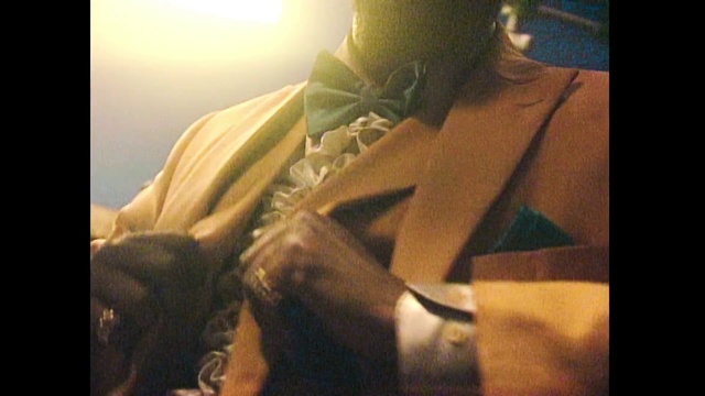 Video Reference: Yellow, Neck, Hand, Mouth, Long hair, Photography, Chest, Black hair, Fashion accessory, Trunk, Person, Man, Photo, Sitting, Table, Front, Holding, Glasses, Wearing, Laptop, Smiling, Phone, Shirt, Woman, Young, Computer, White, Bed