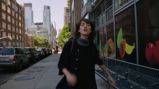 Video Reference: Photograph, Urban area, People, Snapshot, Street, Standing, Pedestrian, Human settlement, Metropolitan area, Fun, Person, Outdoor, Building, City, Sidewalk, Woman, Holding, Man, Walking, Young, Black, Red, Riding, Bus, Clothing, Human face, Jacket, Skyscraper