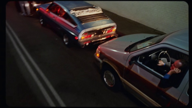 Video Reference: Land vehicle, Vehicle, Car, Mode of transport, Sedan, Model car, Automotive design, Coupé, Automotive exterior, Small, Sitting, Street, Red, Riding, Man, Table, Young, Door, Bed, Driving, Mirror, Cake, Woman, Parked, Road, Holding, City, Room, Racing, Stuffed, Standing, Fire, Phone, People, Wheel, Auto part, Tire, Text