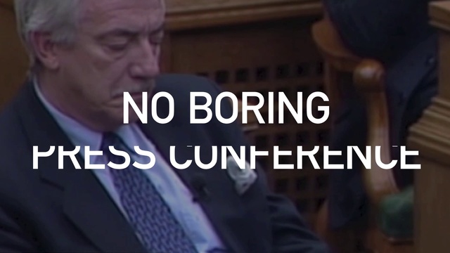 Video Reference: Suit, Text, Font, Photo caption, Gentleman, Photography, Tie, Conversation, Smile, Movie, Person, Man, Holding, Looking, Front, Standing, Sign, Hand, Wearing, Phone, Woman, Red, Talking, White, Shirt, Street, Screenshot, Human face, Clothing