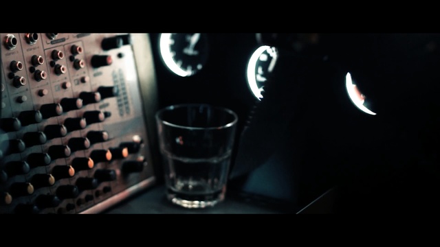 Video Reference: Light, Drink, Font, Drinkware, Photography, Darkness, Alcohol, Glass, Distilled beverage, Still life photography, Indoor, Sitting, Computer, Monitor, Table, Keyboard, Black, Dark, Desk, Laptop, Screen, Front, Small, Cat, Man, Laying, Television, Food, Soft drink, Screenshot, Coffee, Cup