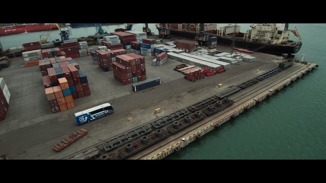 Video Reference: Transport, Freight transport, Aerial photography, Container ship, Mode of transport, Port, Vehicle, Urban area, Ship, Urban design, Indoor, Table, Sitting, Room, Different, Wooden, Desk, Board, Luggage, Man, Suitcase, People, Parked, Group, Bed, Standing, Text, Land vehicle, Car
