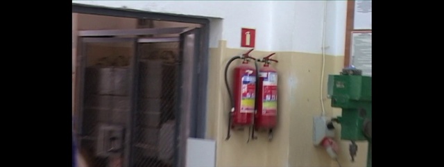 Video Reference: Fire extinguisher, Product, Electrical wiring, Electrical supply, Room, Interior design, Furniture, Person, Indoor, Cabinet, Kitchen, Refrigerator, Small, White, Sink, Counter, Oven, Sitting, Stove, Door, Table, Black, Microwave, Mirror, Computer, Man, Red, Bed, Standing, Shower