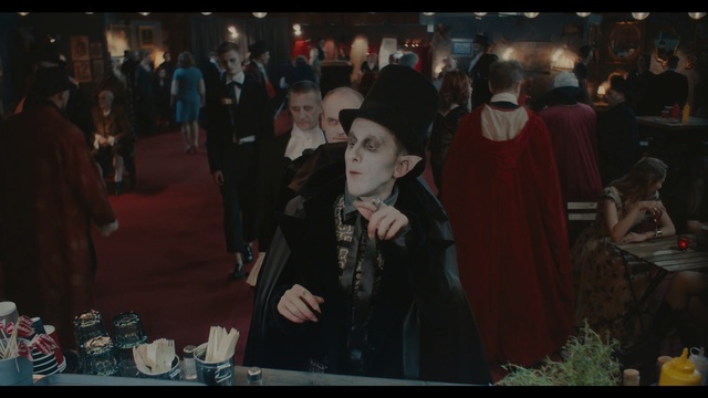 Video Reference: Photograph, Snapshot, Event, Fun, Photography, Screenshot, Crowd, Darkness, Tradition, Visual arts, Person, Indoor, People, Man, Standing, Photo, Table, Woman, Food, Front, Group, Holding, Restaurant, Suit, Room, Large, Cake, Young, Crowded, Pizza, Suitcase, White, Plate, Kitchen, Clothing, Human face