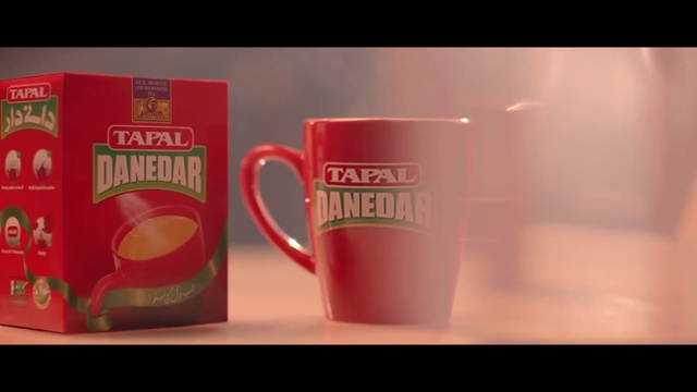 Video Reference: Cup, Mug, Drinkware, Non-alcoholic beverage, Drink, Coffee cup, Tableware, Serveware, Indoor, Table, Sitting, Small, Coffee, Photo, Red, Computer, Orange, Desk, Food, Black, Microwave, Laptop, Wooden, Keyboard, White, Text, Saucer, Tea, Teacup